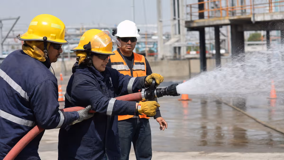 Brigada industrial operando una boquilla profesional durante entrenamiento controlado