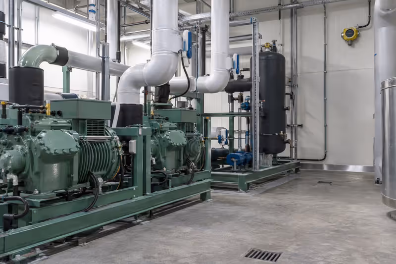 Sala de máquinas de refrigeración con tuberías aisladas y detector fijo en muro alto