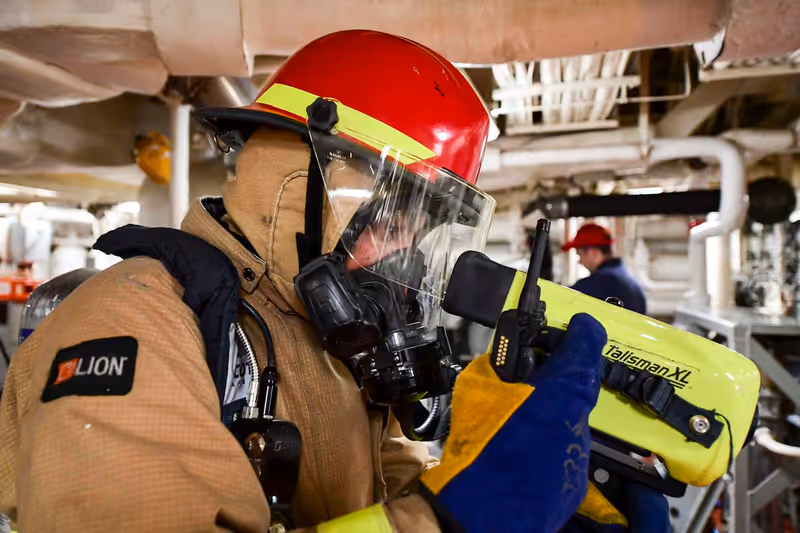 Bombero con equipo de respiración autónoma revisa con una cámara térmica portátil una sala de máquinas