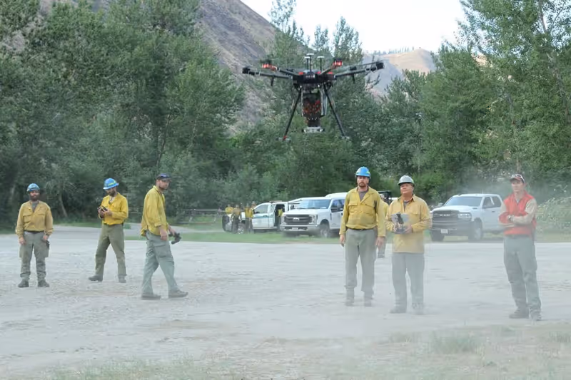 Dron en vuelo sobre un patio de maniobras con vehículos y personal en tierra