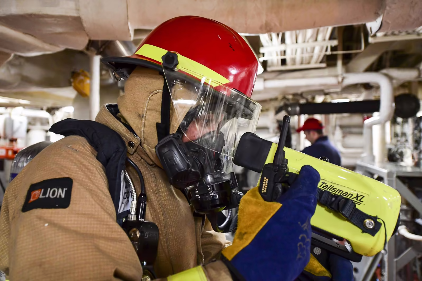 Bombero con equipo de respiración autónoma revisa con una cámara térmica portátil una sala de máquinas