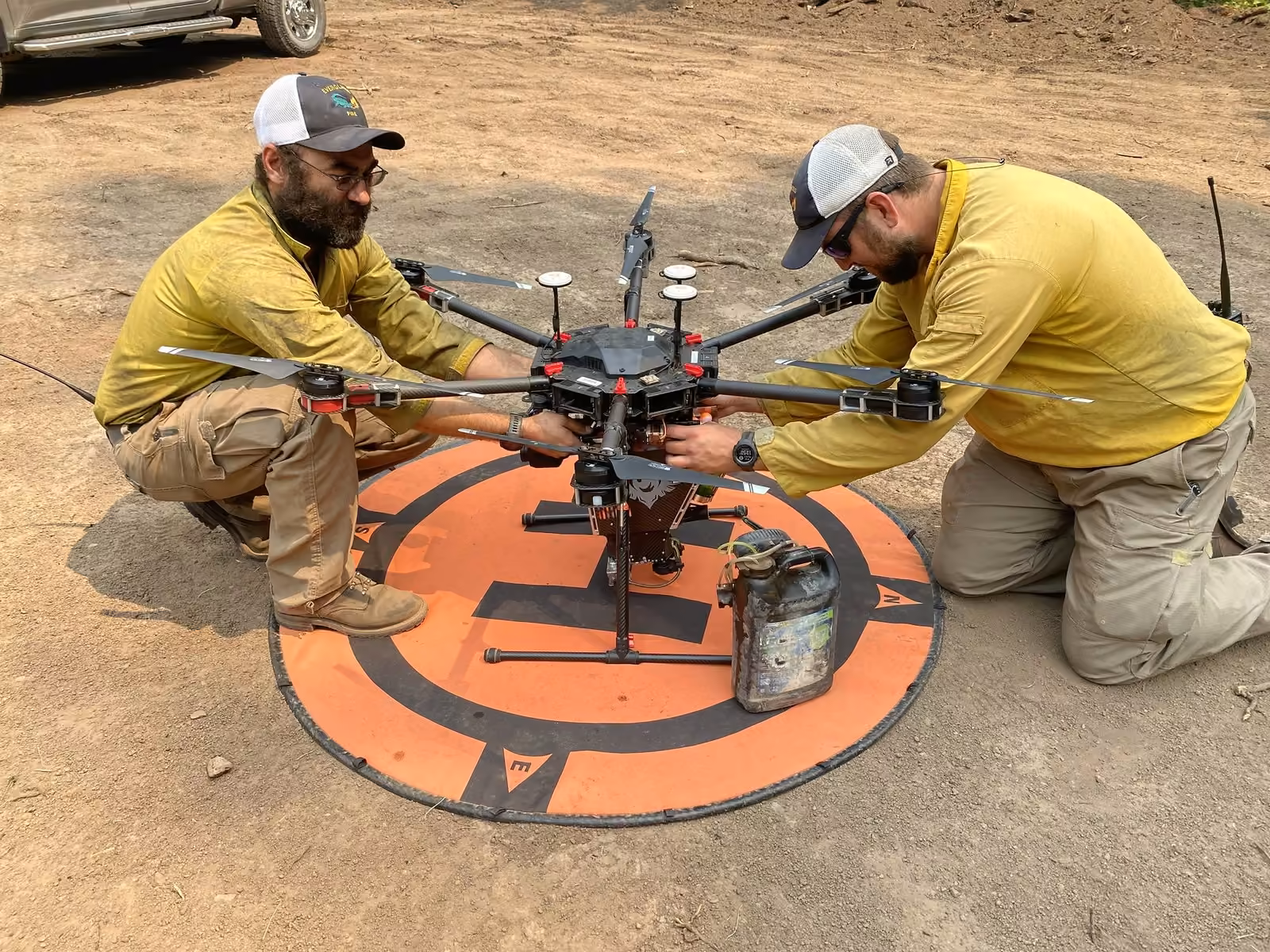 Dos integrantes de una brigada forestal revisan un dron hexacóptero sobre su plataforma antes del vuelo